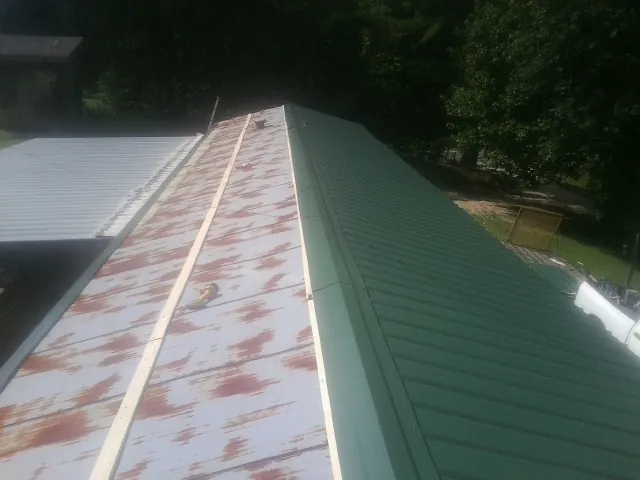 Old rusted panels beside newly installed green metal roofing — Wind Damage Roof Repair by Roofing Brothers in Humboldt